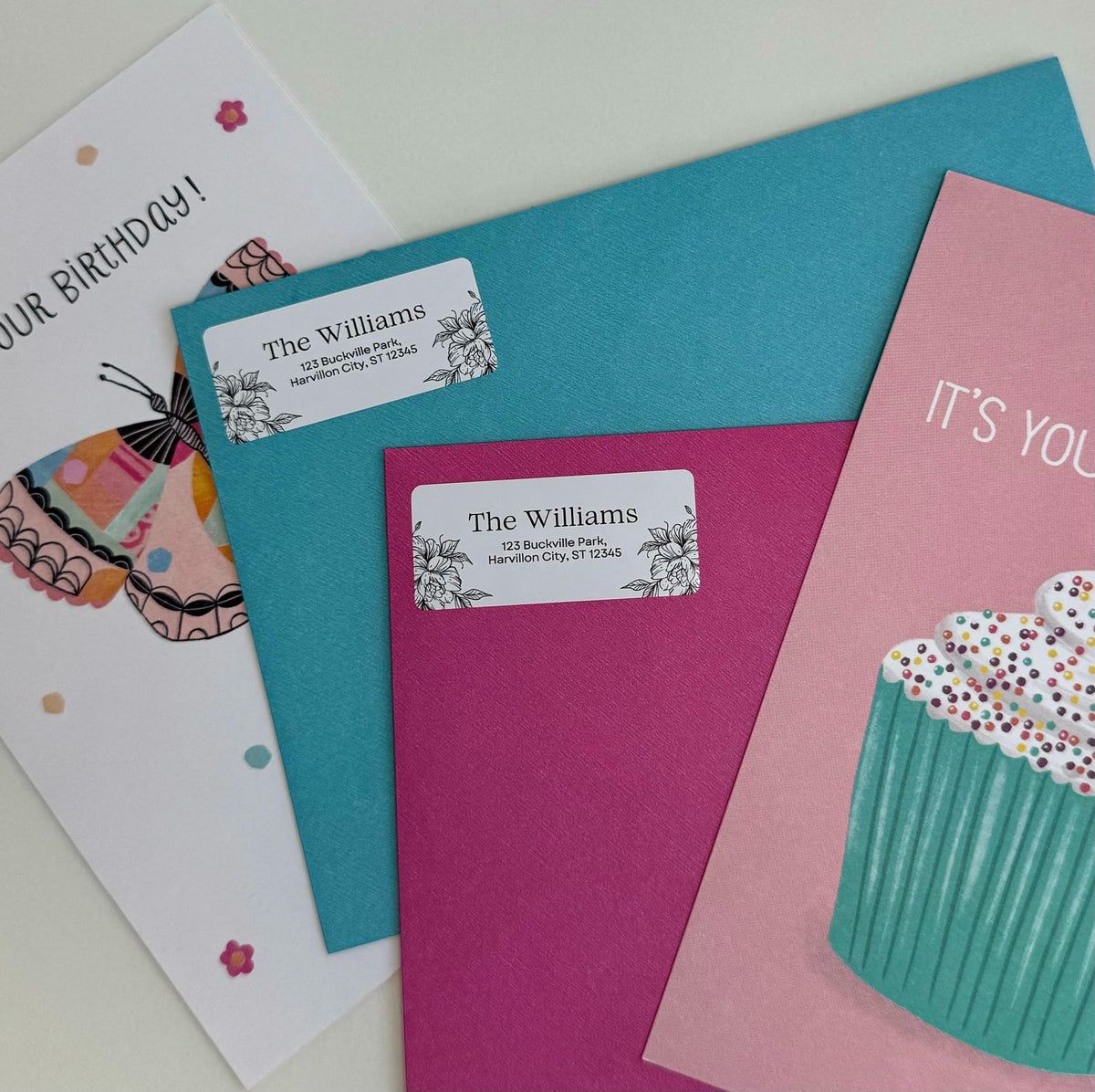 Floral return address labels on teal and pink envelopes beside colorful birthday cards