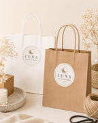 Luna Candle Studio round logo stickers on a white paper shopping bag and a kraft paper shopping bag