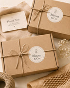 Bloom & Co. round logo stickers on twine-tied kraft mailer boxes beside a thank-you card